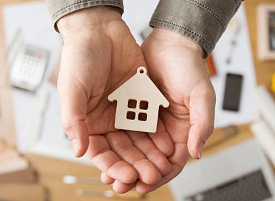 Image of a hand holding a little house ornament purely for visual purposes